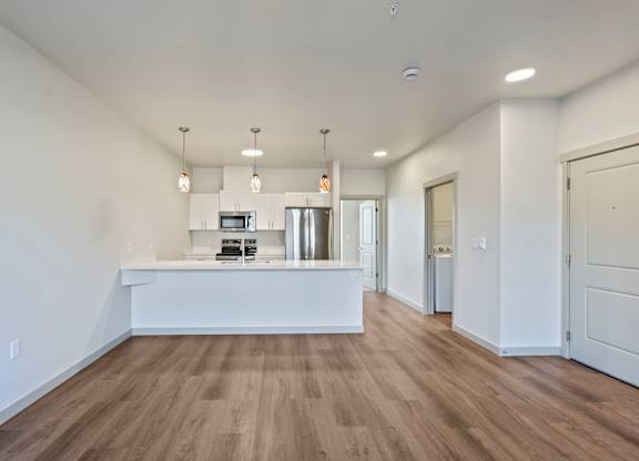 A spacious room with a long white counter and wooden flooring.