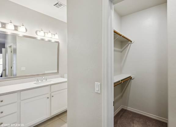 A white bathroom with a sink, mirror, and a closet.