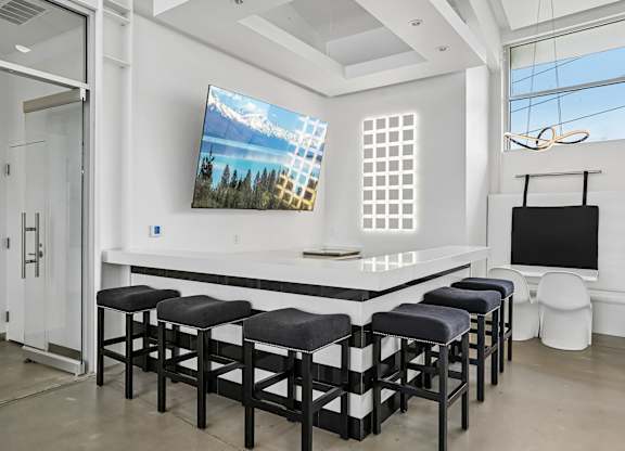 A modern bar area with a large screen TV mounted on the wall.
