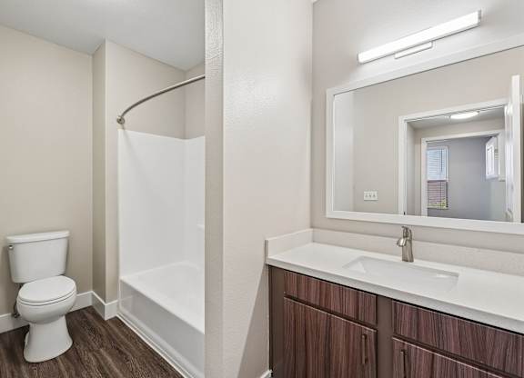 A white toilet sits next to a white bathtub in a bathroom.