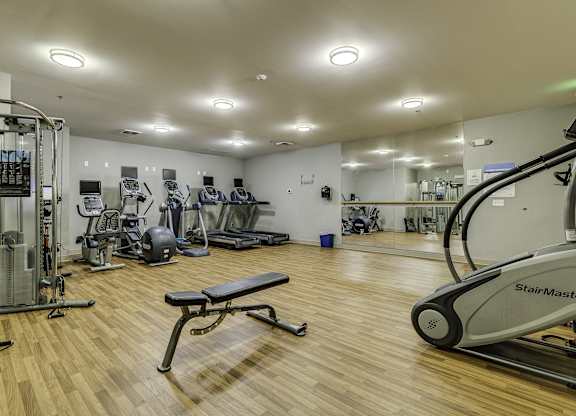 A gym with a variety of equipment including treadmills, weights, and exercise machines.