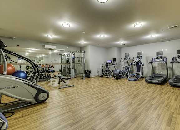 A gym with a variety of equipment including treadmills, stationary bikes, and weight machines.
