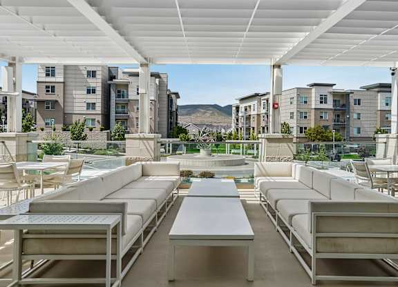 A patio with white furniture and a table is covered by a white roof.