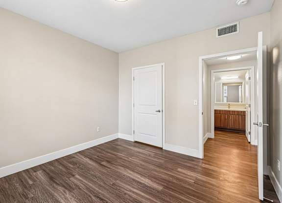 A room with a white door and a wooden floor.