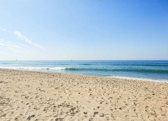 A sandy beach with waves coming in from the ocean.