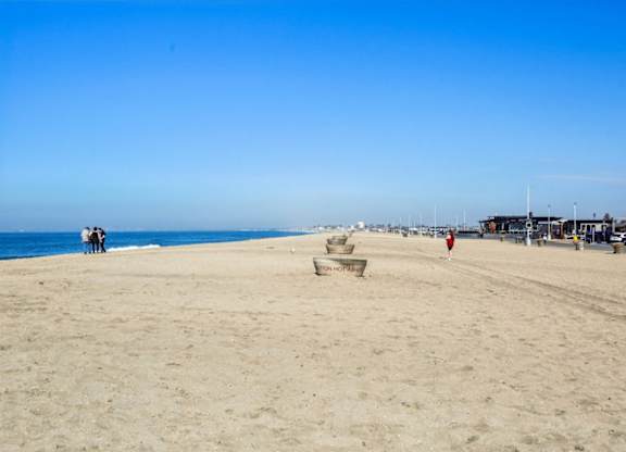 A beach with people and chairs under a clear sky.