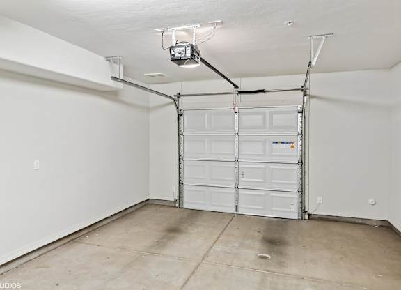 A garage with a white door and a concrete floor.