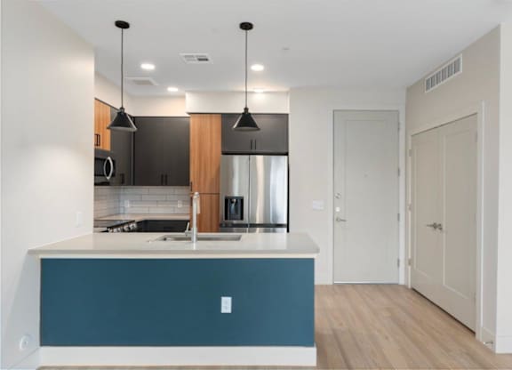 a renovated kitchen with a blue island and a stainless steel refrigerator