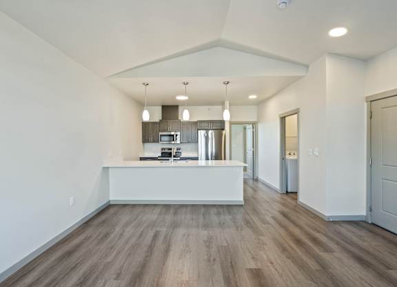 A spacious kitchen with a white countertop and wooden flooring.