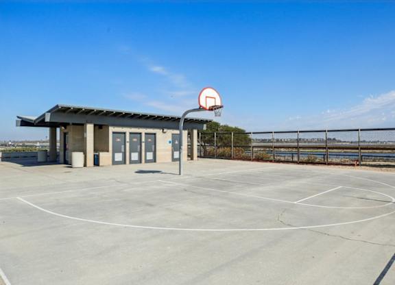 A basketball court with a basketball hoop and a small building.