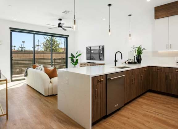 A modern kitchen with a white countertop and wooden cabinets.
