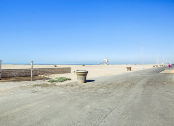 A road with a wall and a trash can in the middle.