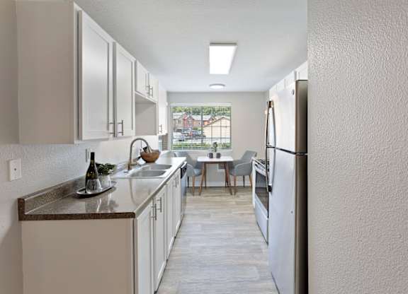 A kitchen with white cabinets and a wooden floor.