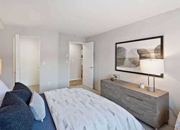 A bedroom with a bed, nightstand, and a painting on the wall.