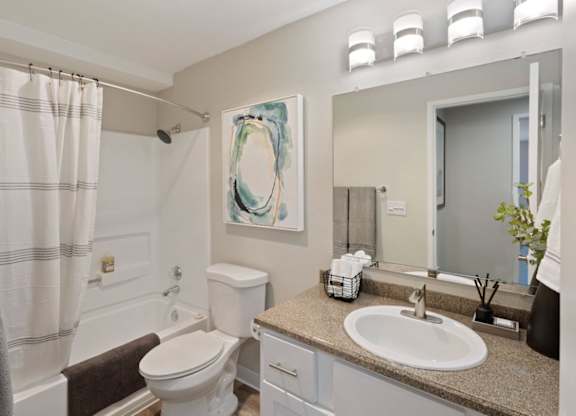 A bathroom with a toilet, sink, and mirror.