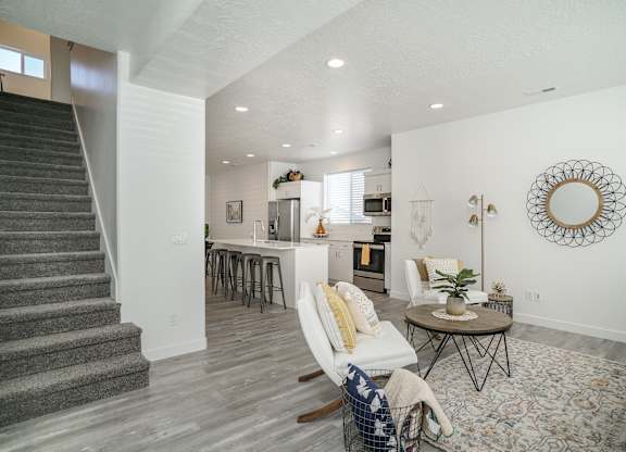a living room with a staircase and a kitchen