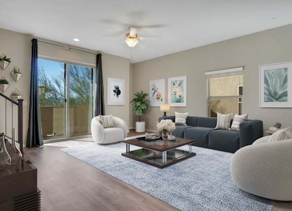 A modern living room with a grey sofa, a white armchair, a coffee table, and a ceiling fan.