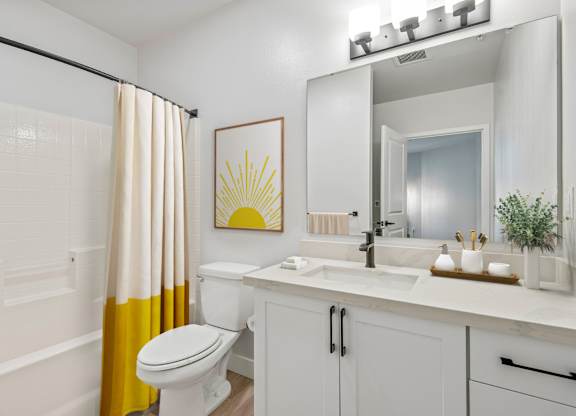 A bathroom with a white toilet, sink, and a yellow shower curtain.