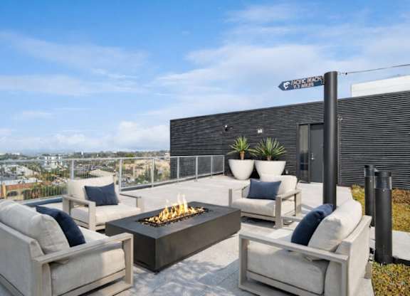 A patio with a fire pit and couches.