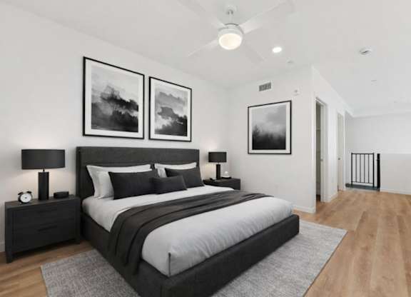 A bedroom with a large bed, two nightstands, and pictures on the wall.
