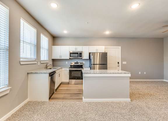 A kitchen with white cabinets and a large island.at Four Cedars, Gunter, TX 75058