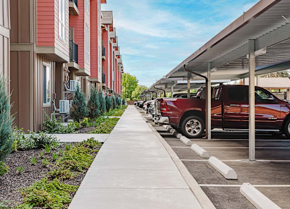 A red car is parked in a parking lot next to a building.