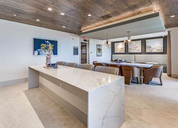 A modern kitchen with a marble island and wooden ceiling.
