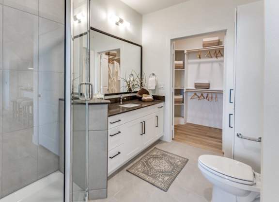 A bathroom with a toilet, sink, and mirror.