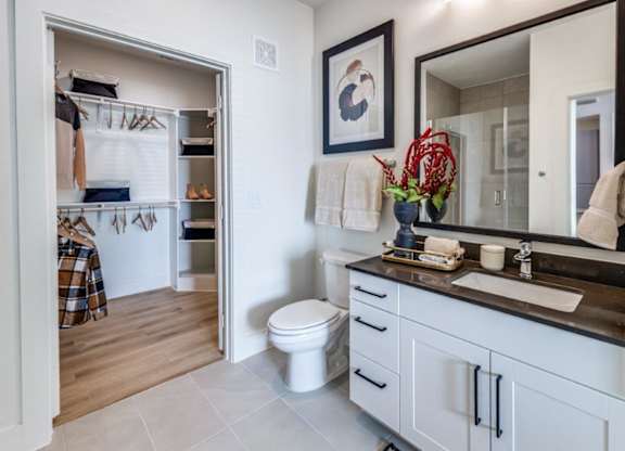 A bathroom with a toilet, sink, and mirror.