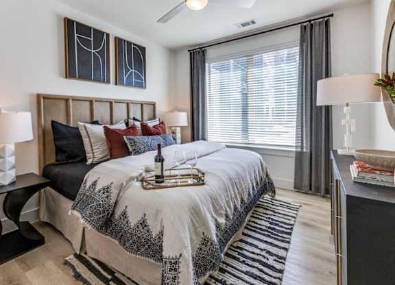 A bedroom with a large bed and a window with blinds.