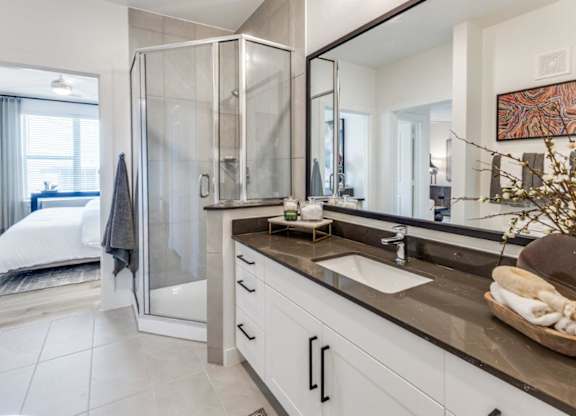 A modern bathroom with a walk-in shower and double sinks.