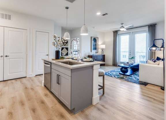 A modern kitchen with wooden floors and white cabinets.
