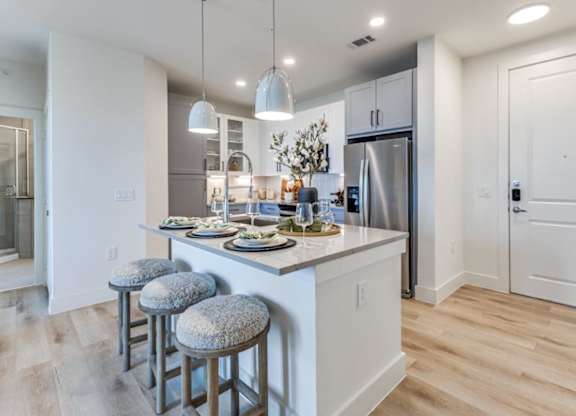 A kitchen with a bar stool and a refrigerator.