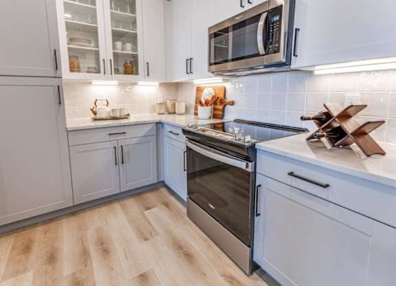 A kitchen with a wooden floor and a stainless steel oven.