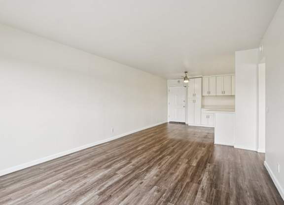 Empty room with wooden flooring and white walls.
