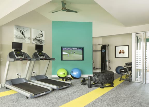 a home gym with a green accent wall and a yellow stripe on the floor