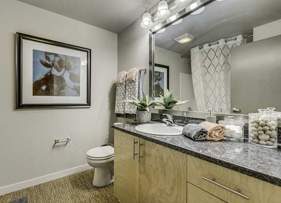 A bathroom with a toilet, sink, and a mirror.