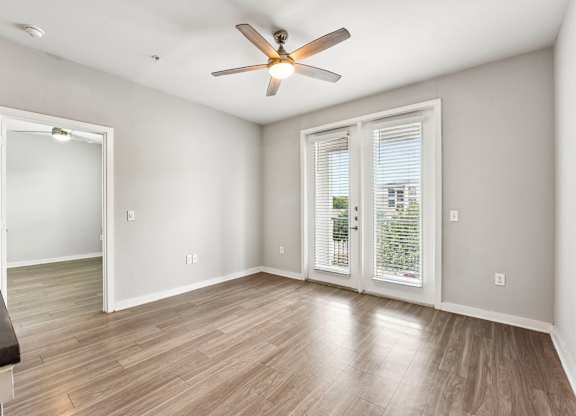 A room with a ceiling fan and wooden flooring.