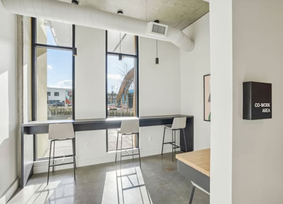 A room with a long table and chairs with a sign on the wall that says "CO-WORK AREA".