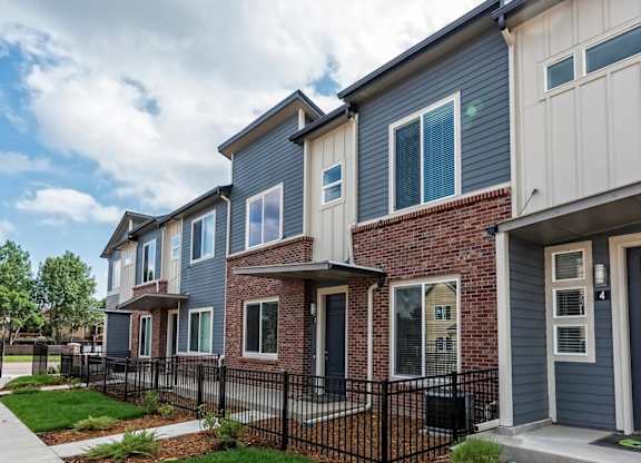 A row of houses with a black fence in front.