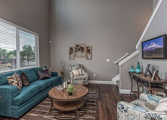 A living room with a green couch, a coffee table, and a TV on the wall.