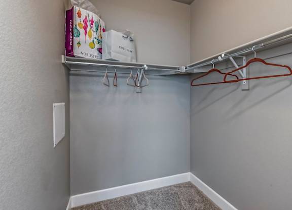 A closet with a grey wall and a red hanger.