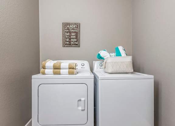 Two white washing machines with towels on top.