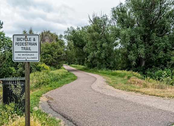 A sign on a path indicates that it is a bicycle and pedestrian trail.