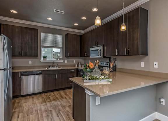A kitchen with brown cabinets and a wooden floor.