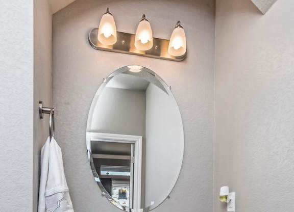 A white sink with a round mirror above it.