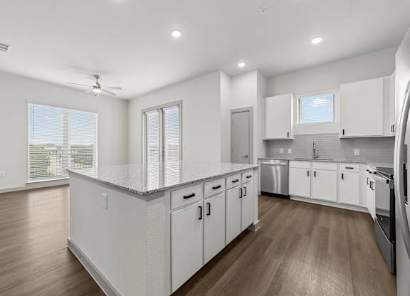 A modern kitchen with white cabinets and wooden floors.