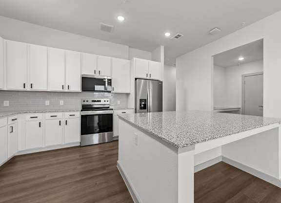 A kitchen with white cabinets and a granite countertop.