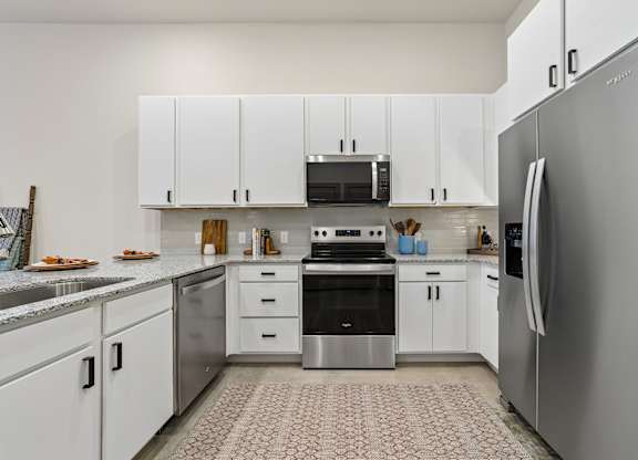 A modern kitchen with white cabinets and stainless steel appliances.