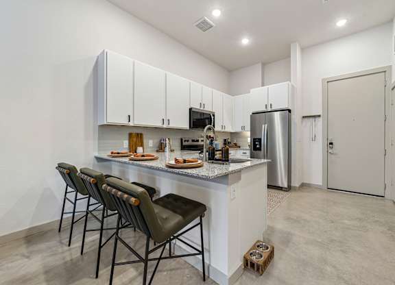 A kitchen with white cabinets and a white countertop with a refrigerator and a sink.
